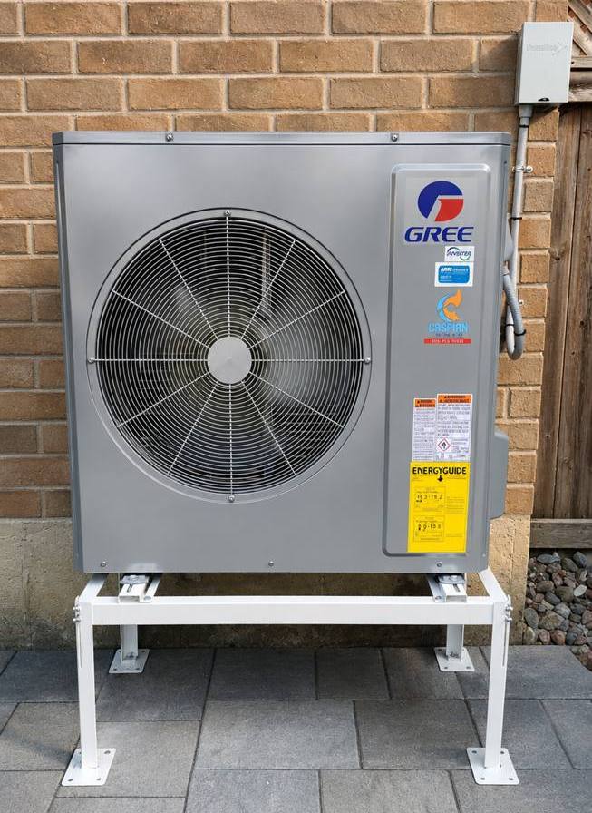 Cold-climate heat pump installed by Caspian on a raised stand beside a GTA home, with Caspian's install sticker on the unit
